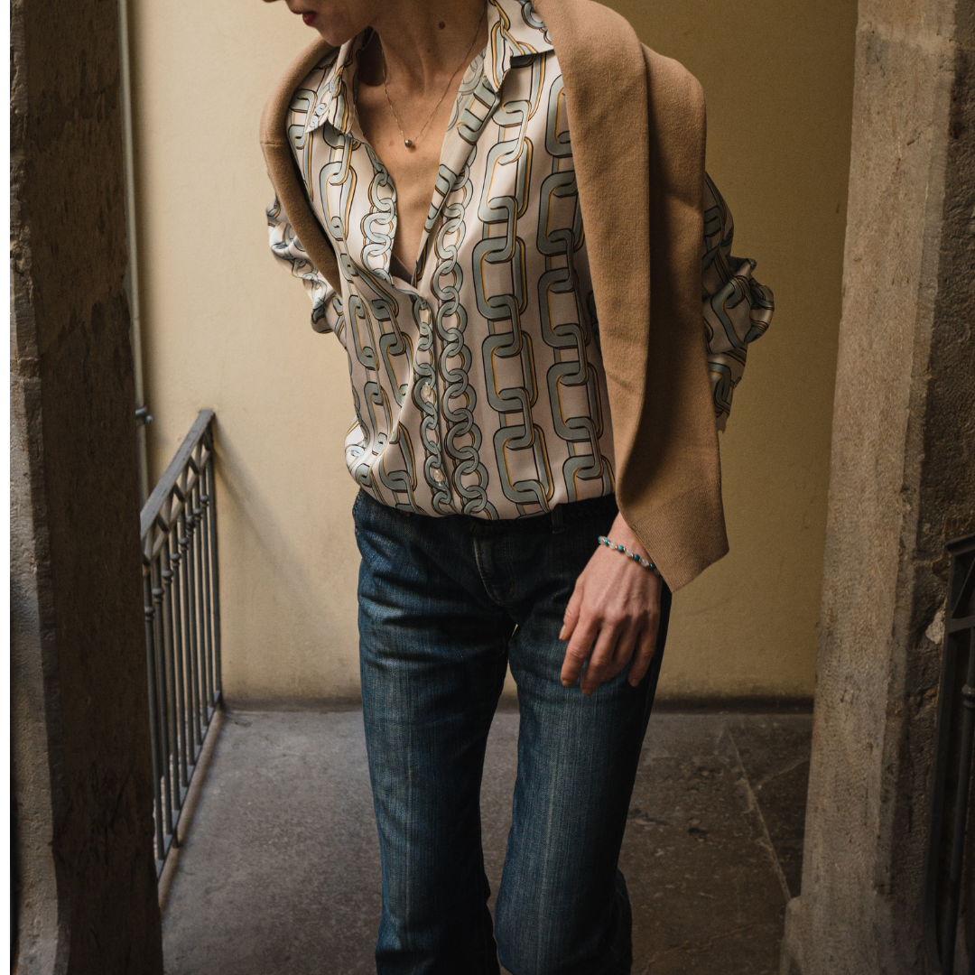 Femme dans des escalier mettant en avant son bracelet  Détoxifiant  composé de pierre naturelle d'Apatite bleue et Pierre de Lune , alternant avec de petites billes en or , avec une seule pierre de quartz rutile en son centre, ainsi qu'un noeud en or